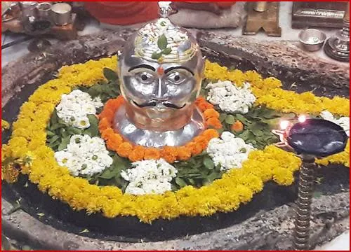 Silver mukhavata of Lord Shiva decorated with marigold and white flowers